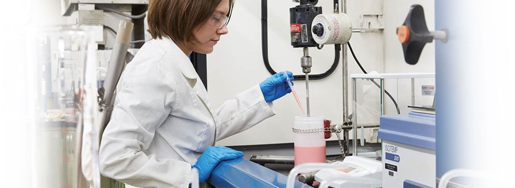 Woman in lab coat mixing pink solution for custom product development