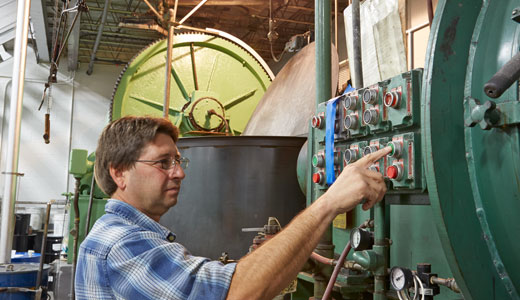 Man in plaid shirt pushing the green button on a green compounding machine