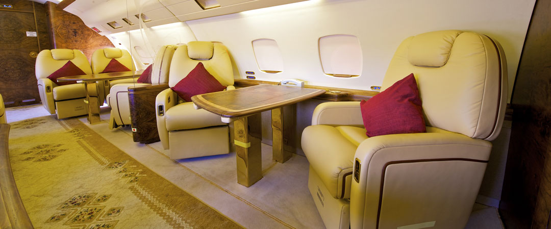 A luxury airplane with red carpet pillows and white couch like seats