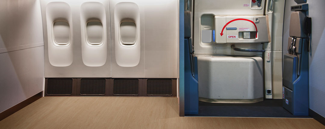 Interior of an airplane with tan wood like non-textile flooring near exit