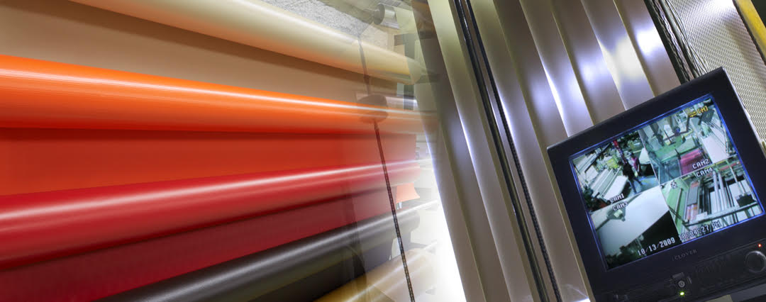 Security monitors watching the manufacturing process with rolls of colorful vinyl next to the window