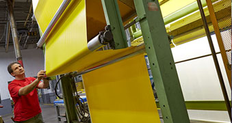 Man in red shirt, operating a vinyl roller with yellow vinyl