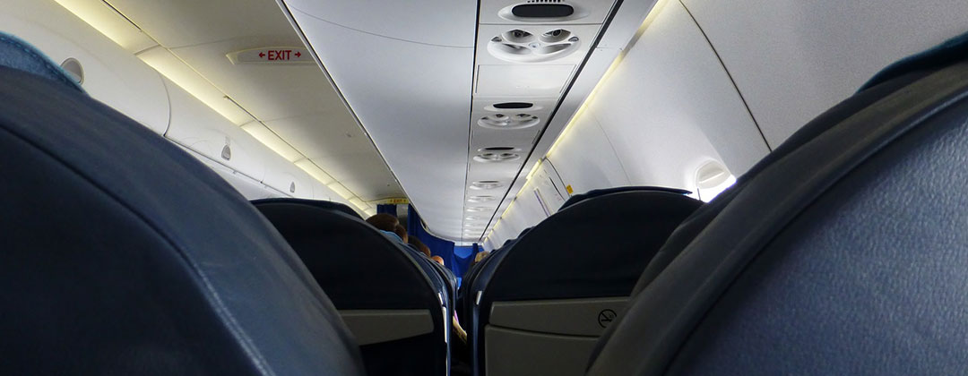 Tops of blue airplane seats and the ceiling of the airplane