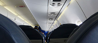 Tops of blue airplane seats and the ceiling of the airplane