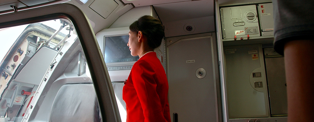 Flight attendant standing inside the doorway of a plane