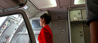 Flight attendant standing inside the doorway of a plane