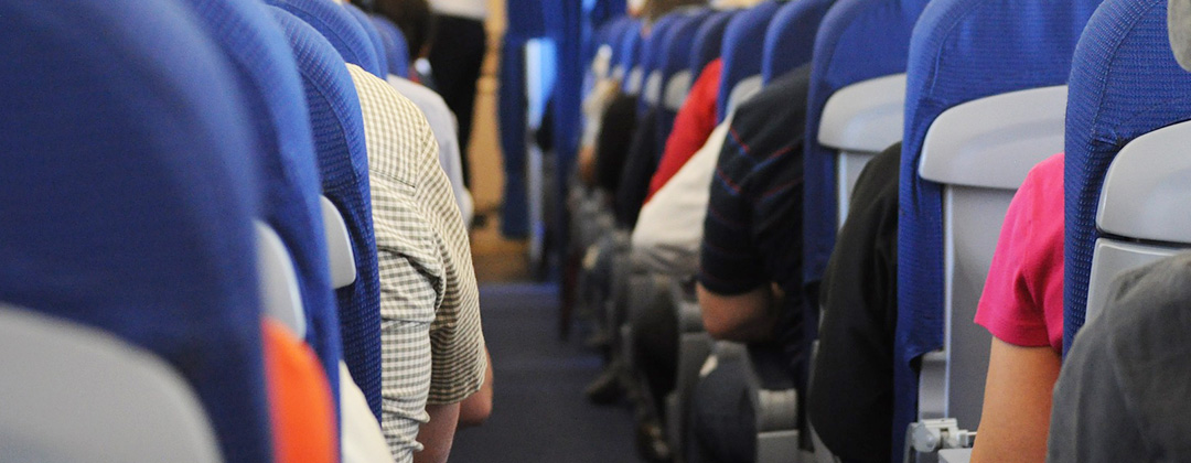 Airplane aisle of blue seats and people's shoulders